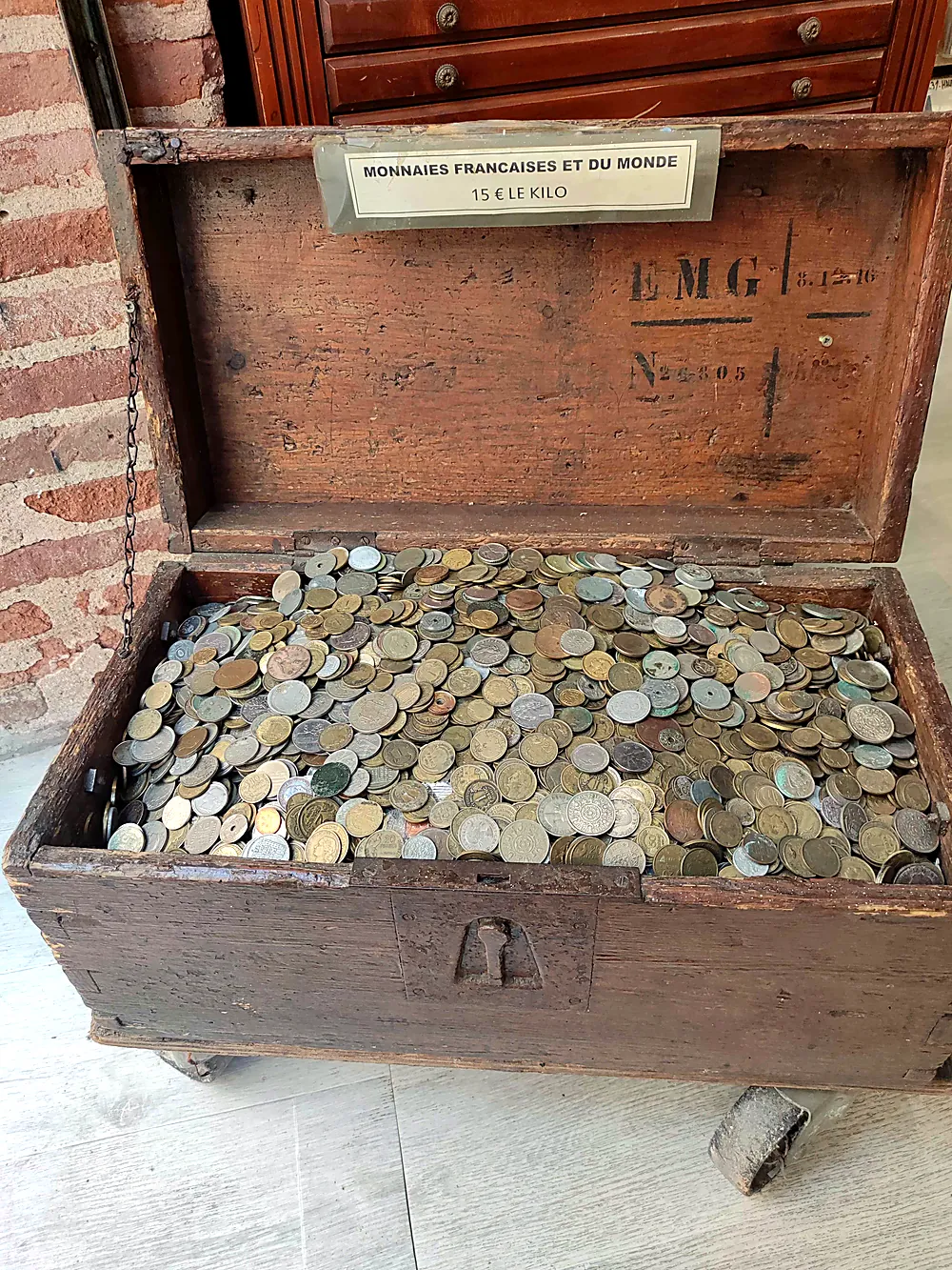 Coffre en bois ancien rempli de monnaies françaises et du monde vendues au kilo